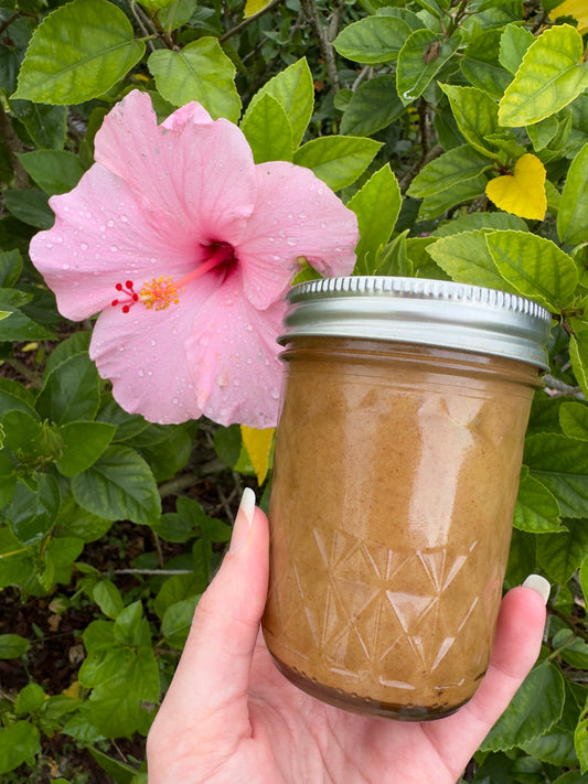 GRASSFED BROWN BUTTER INFUSED WITH CINNAMON AND VANILLA. SWEETENED WITH RAW HONEY IN A GLASS JAR NEXT TO HIBISCUS FLOWER.